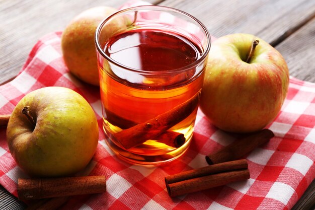 Cidre de pomme avec des bâtons de cannelle et des pommes fraîches sur fond de bois