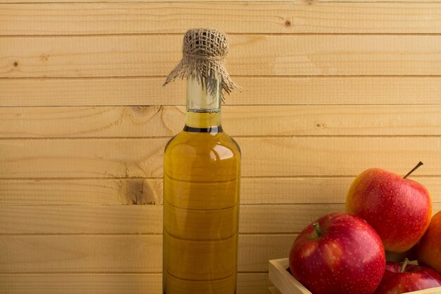 Cidre de vinaigre de pomme dans la bouteille en verre sur le bois