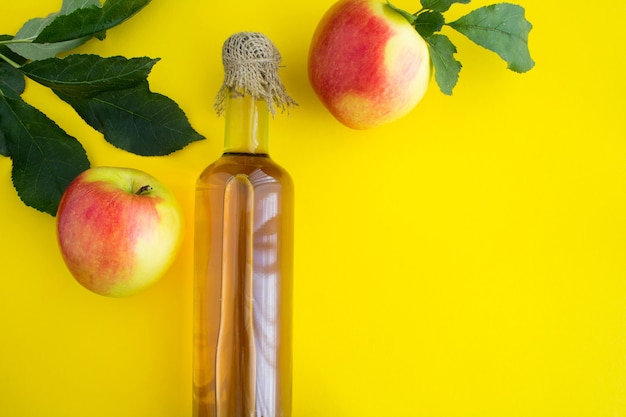 Cidre de vinaigre de pomme dans la bouteille en verre sur la table jaune.Vue de dessus.Copier l'espace.