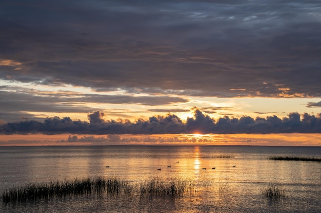 Le ciel au coucher du soleil avec des nuages sur le lac le soleil se couchant lentement sur l'étang avec les canards le transforme en orange coloré