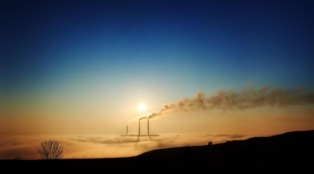 Ciel bleu au-dessus des cheminées thermiques entourées de fumée