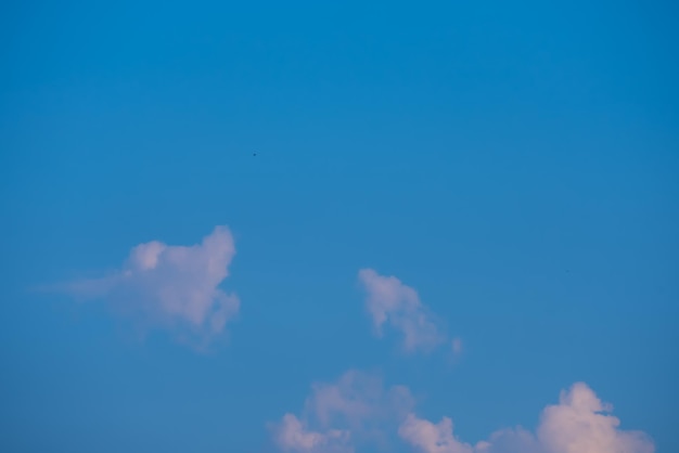 Un ciel bleu clair avec des nuages et un oiseau au milieu