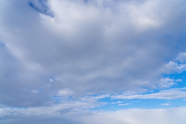 Un ciel bleu avec des nuages et une personne en chemise rouge regarde le ciel.