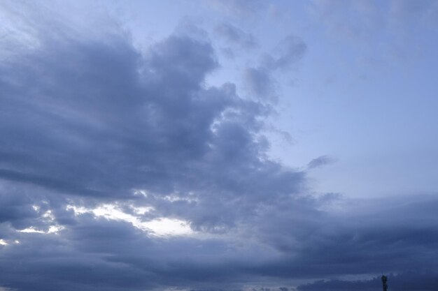 Un ciel bleu avec des nuages et le soleil qui brille à travers les nuages.