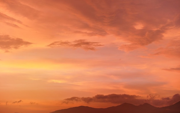 Ciel calme orange et rose au coucher du soleil, silhouettes de montagnes en contrebas - peut être utilisé comme arrière-plan avec des sujets placés devant