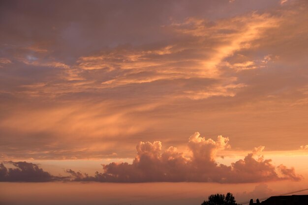 Ciel de coucher de soleil coloré et lumineux avec des nuages lisses et vifs illuminés par la lumière du soleil couchant se propageant à l'horizon