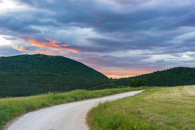 Ciel dramatique au coucher du soleil sur une route de campagne dans la région des Marches en Italie Nuages épiques au-dessus d'un sentier sinueux collines et montagnes uniques paysage sentiment émotionnel concept