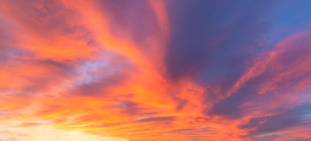 Ciel dramatique coloré du lever du soleil au coucher du soleil avec des nuages texturés dans des tons or bleu.