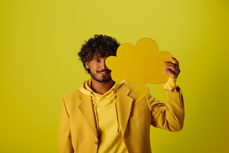 Photo le ciel ensoleillé, l'homme en veste jaune tenant un nuage découpé