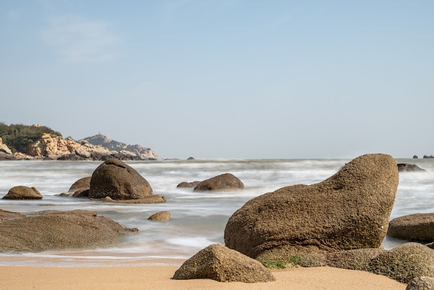 Le ciel est bleu en été. La mer a des plages dorées, des vagues et des récifs