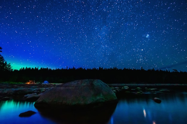 Ciel étoilé avec constellations galaxies voie lactée et de nombreuses étoiles au-dessus de l'eau de la rivière avec des pierres