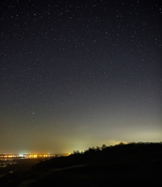 Ciel étoilé la nuit sur la ville et la forêt. Paysage avec une longue exposition.