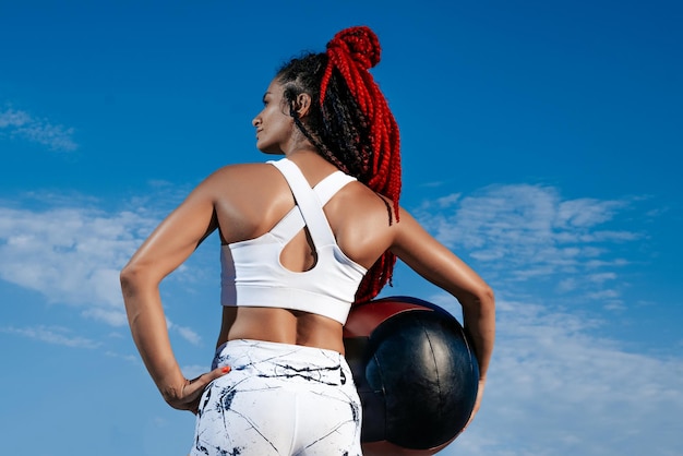 Ciel de fond De l'arrière Femme athlétique avec ballon med Force et motivationPhoto de femme sportive en vêtements de sport à la mode