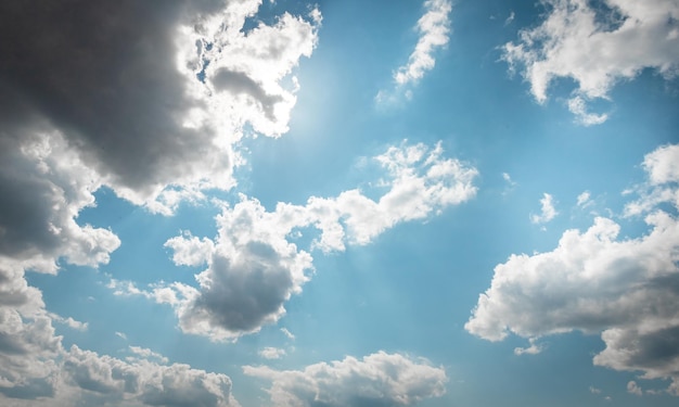 CIEL DE JOUR AVEC DES NUAGES BLEUS ET BLANCS et un rayon de soleil derrière