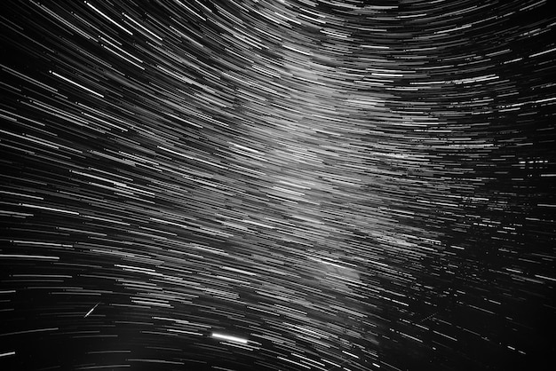 Ciel nocturne avec beaucoup de traînées d'étoiles brillantes. Abstrait astro naturel. Noir et blanc.