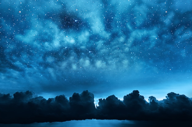 Ciel nocturne avec étoiles et lune et nuages.