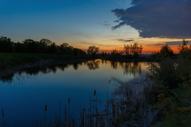 Le ciel avec des nuages lumineux éclairés par le soleil après le coucher du soleil sur le lac.