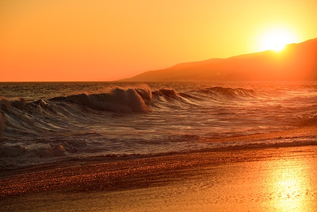 Ciel d'or et plage tropicale d'eau de mer avec vague lisse et ciel coucher de soleil fond abstrait soleil d'or