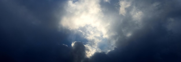 Ciel orageux foncé avec un nuage blanc illuminé par le soleil au milieu