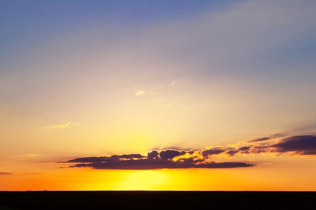 Ciel pittoresque au coucher du soleil et étroite bande de champ sombre