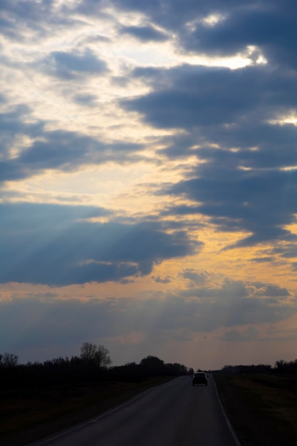 Ciel sombre du soir et une voiture qui s'éloigne le long de l'autoroute