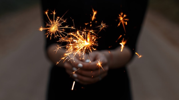 Cierge magique de fête incroyable entre les mains d'une jeune femme