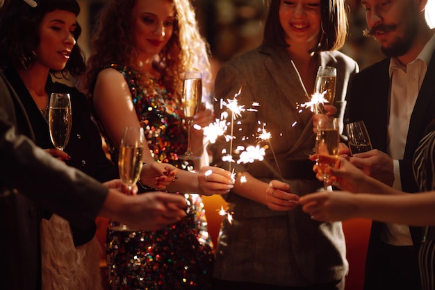 Photo des cierges étincelants dans les mains jouer un feu d'artifice pour célébrer les vacances d'hiver magic new year