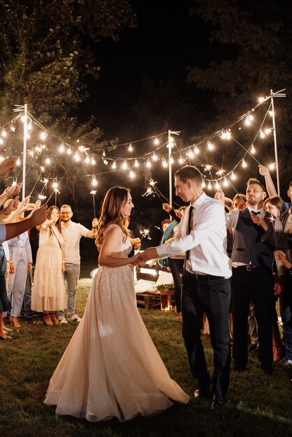 Des cierges magiques au mariage des jeunes mariés entre les mains d'invités joyeux