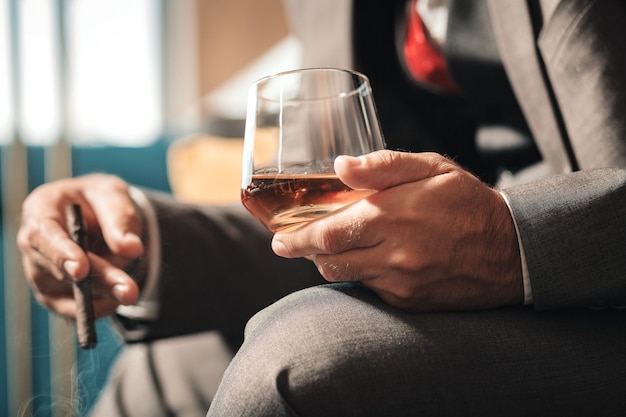 Cigare après le travail. Homme d'affaires d'âge mûr portant montre à la main fumant un cigare après une dure journée fatigante au travail