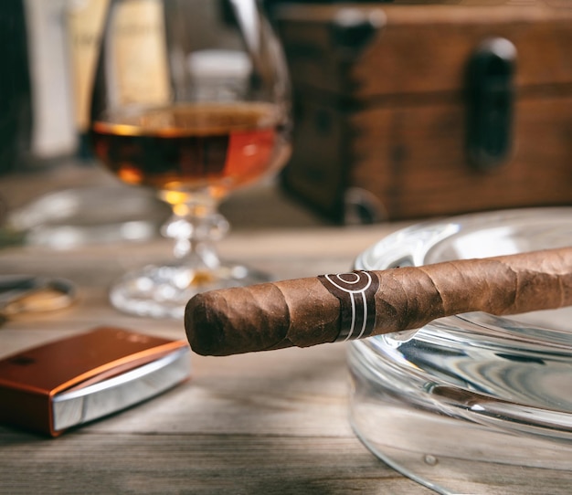 Un cigare cubain dans un cendrier sur un bureau en bois.