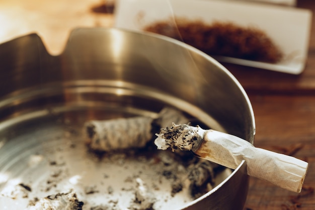 Cigarette allumée dans un cendrier en métal photo en gros