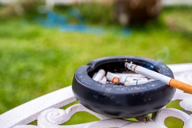 Cigarette allumée avec de la fumée sur un cendrier en céramique