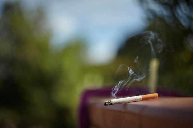 Cigarette allumée et posée sur le mur en attente d'être fumée.