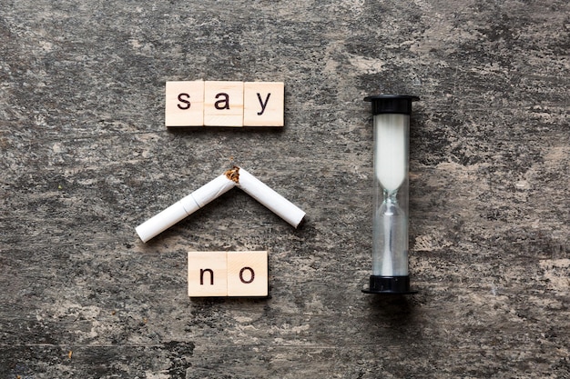 Cigarette et blocs de bois Cigarette cassée sur fond de table avec sablier Journée sans tabac avec horloge sablier concept de santé temps pour arrêter de fumer