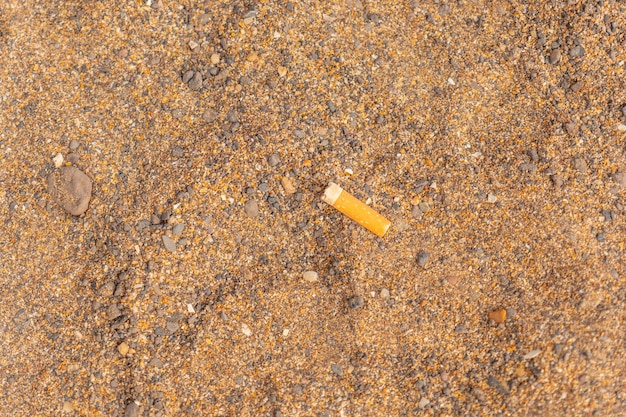 Une cigarette posée sur le sable de la plage