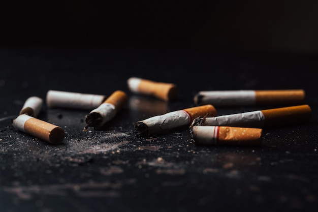 Les cigarettes ont été brûlées et fumées. La Journée mondiale sans tabac tombe le 31 mai de chaque année. Les cigarettes à fumée ont été brisées, sur un sol noir.