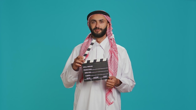 Un cinéaste du Moyen-Orient tient un clapboard.