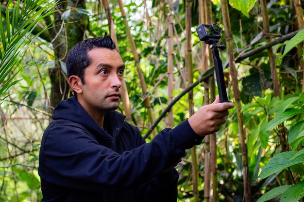 Un cinéaste professionnel en train d'enregistrer une vidéo avec une caméra d'action dans une forêt.