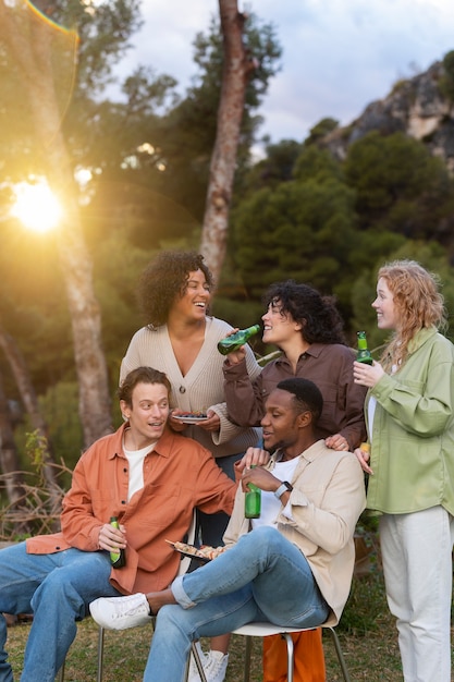 Photo cinq amis buvant de la bière et parlant lors d'une fête en plein air