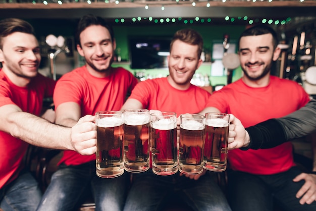 Cinq fans de sport buvant de la bière au bar.