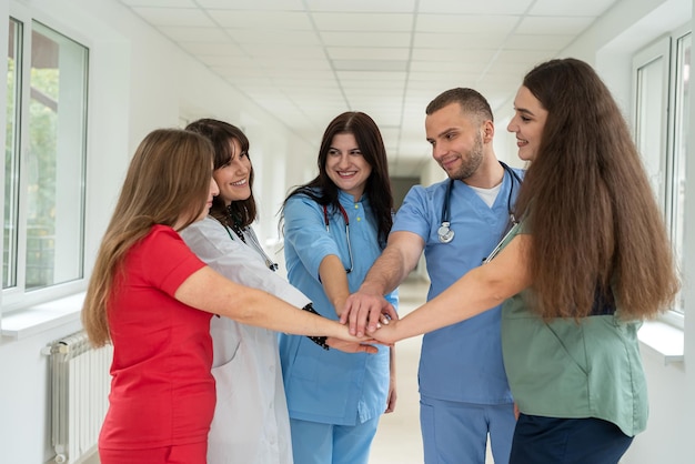 Cinq médecins d'une équipe médicale s'accrochent les mains, collaborent et soutiennent dans un hôpital.