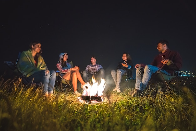 Les cinq personnes se reposent près du feu de joie. le soir la nuit