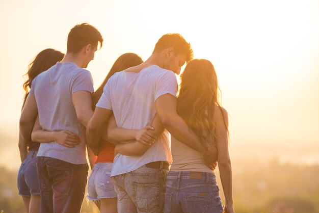 Les cinq personnes se tiennent sur le fond du coucher de soleil