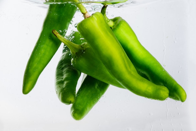 Cinq poivrons jalapeño dans de l'eau avec des bulles.