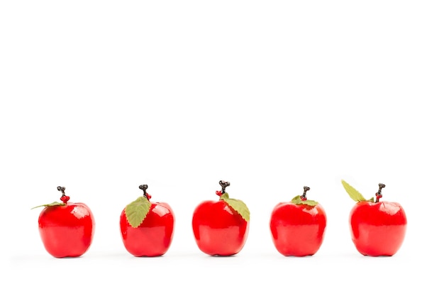 Cinq pommes en plastique rouges sur fond blanc