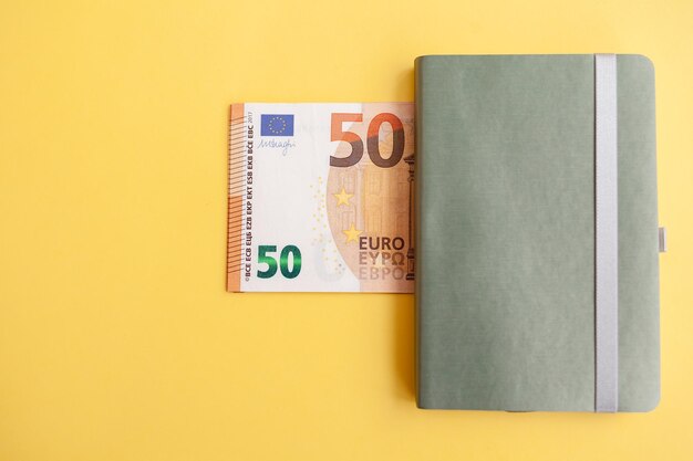 Cinquante billets en euros à l'intérieur d'un portefeuille noir sur fond jaune