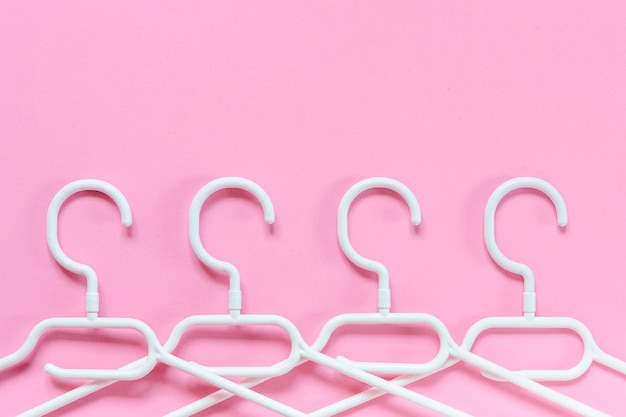 Cintres en plastique blanc sur fond rose Concept à vendre boutique plateforme de revente de marques de commerce en ligne d'occasion