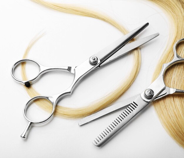 Photo des ciseaux de coiffeur avec une mèche de cheveux blonds isolés sur du blanc