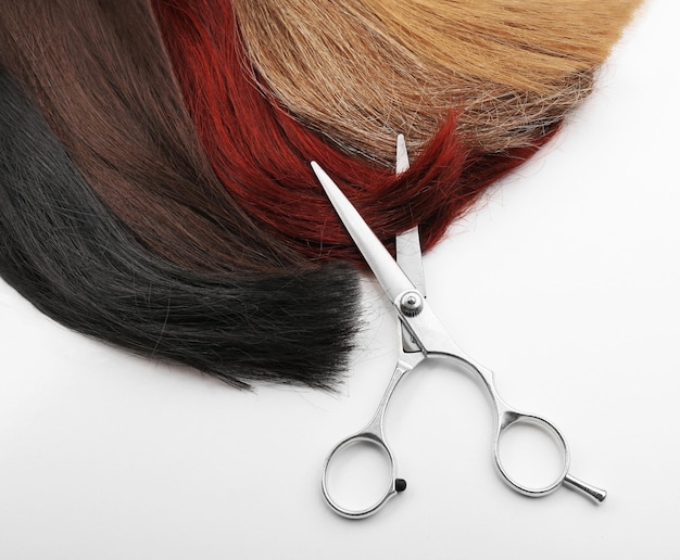 Ciseaux de coiffeur avec mèches de cheveux multicolores isolés sur blanc