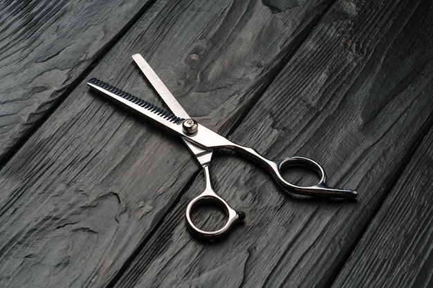 Photo des ciseaux de coiffure sur fond de bois noir en gros plan